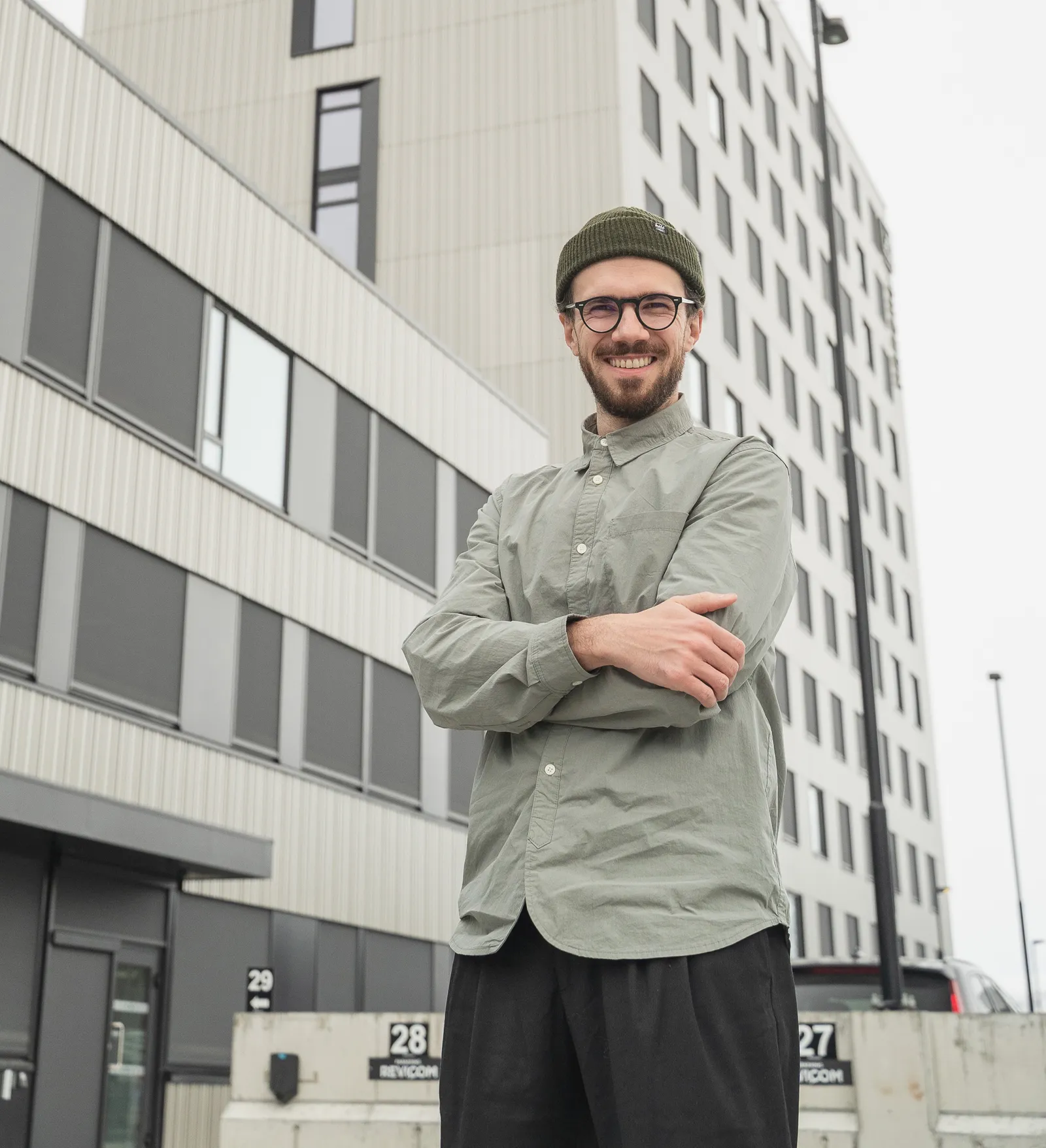 Radu smiling with his arms crossed, in front of grey office buildings