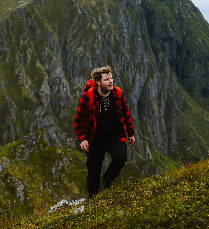 Vegard on a steep green mountainside, in a red checked shirt